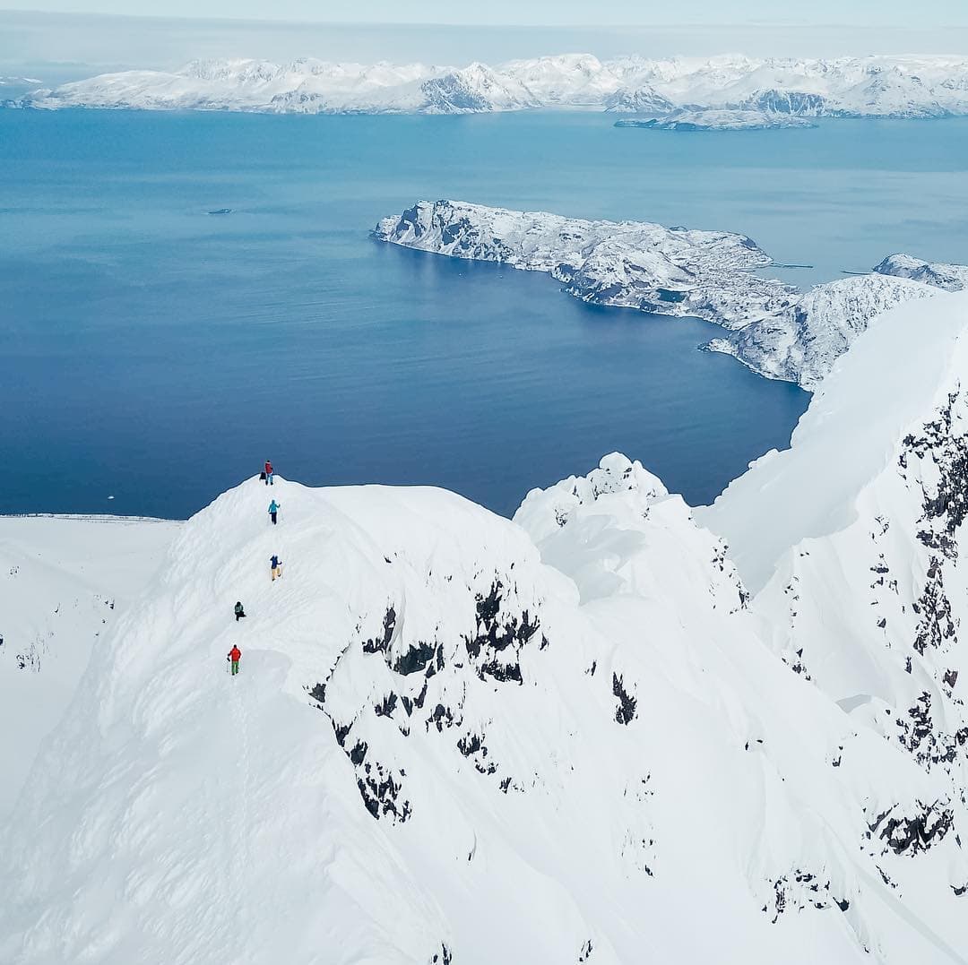 A group of people hiking a snowy mountain in the Lyngen Alps