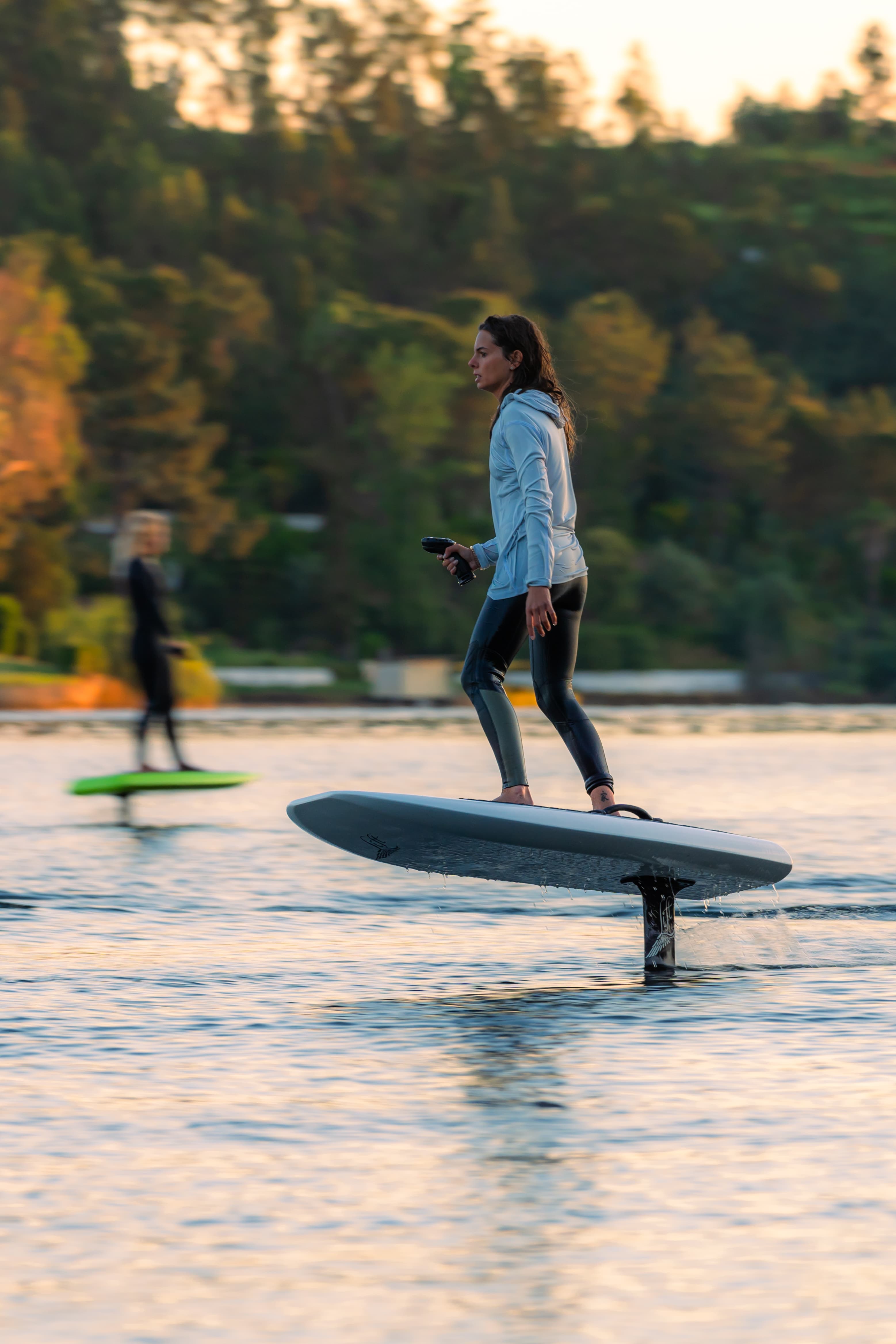 Girl efoiling in the sunset with the remote controller in her hand. Beautiful evening light.