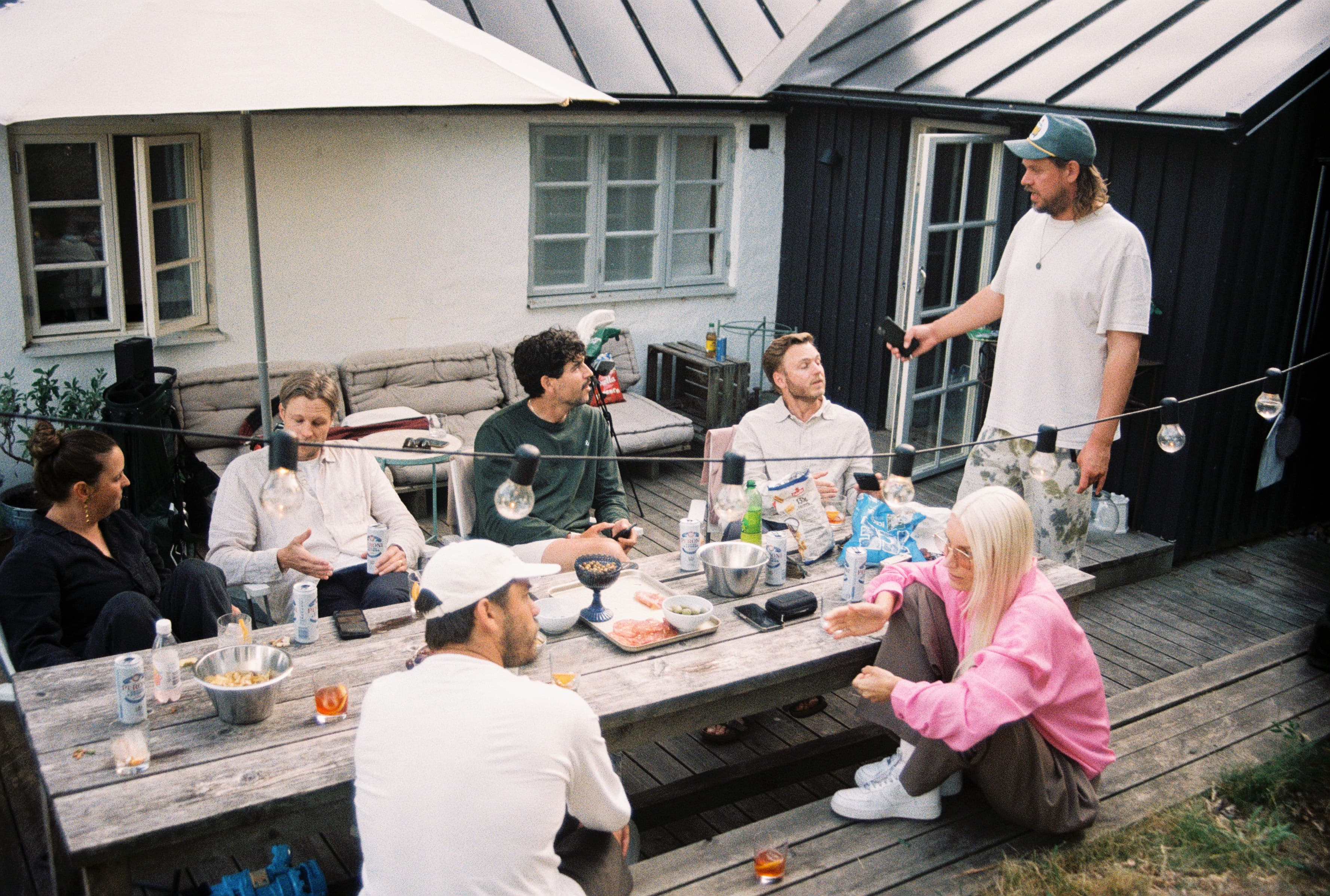 Friends eating in a wooden table outside cozy Midsummer Lunch