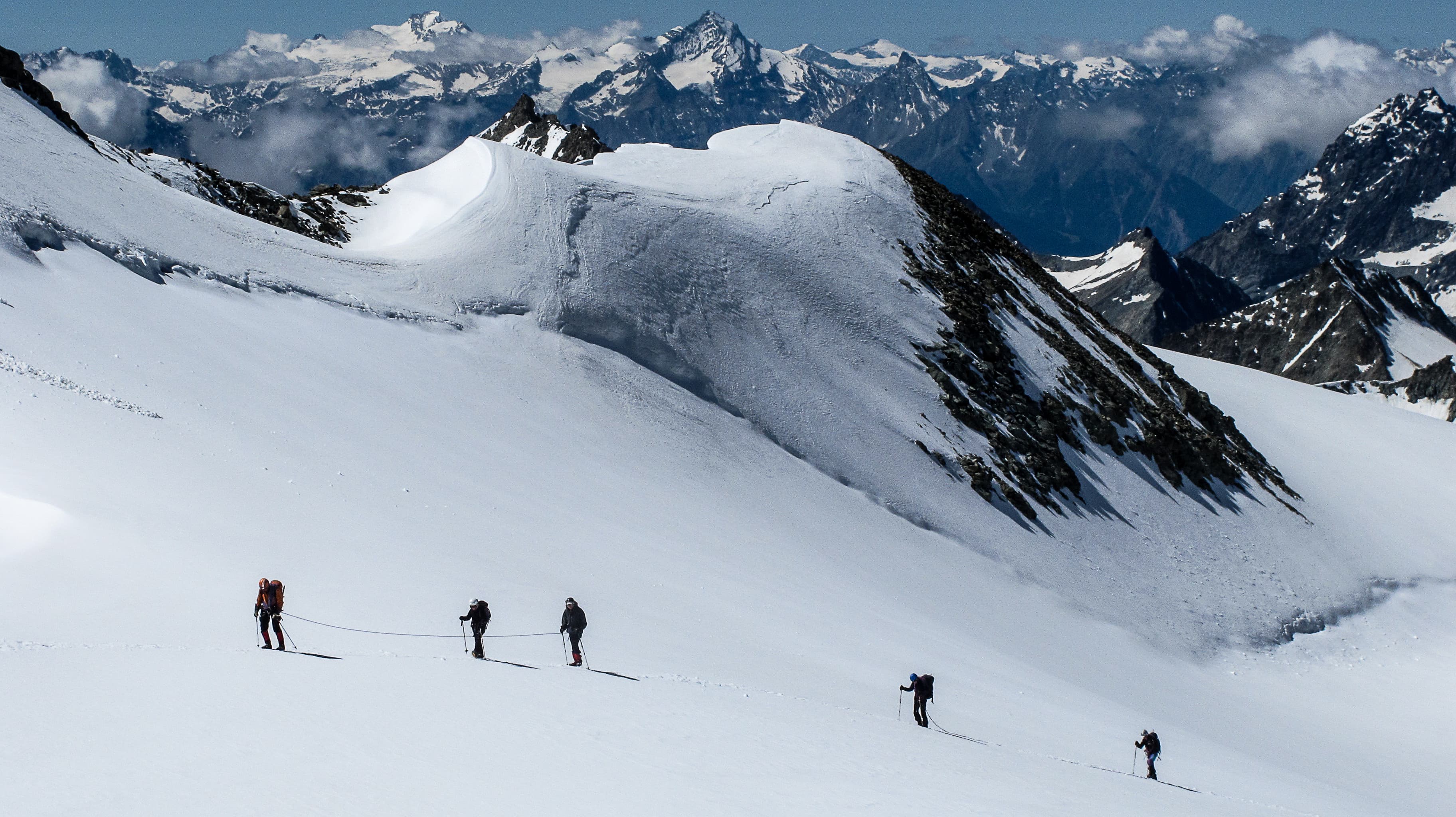 Skiers with ropes hiking up a mountain in the French ALps