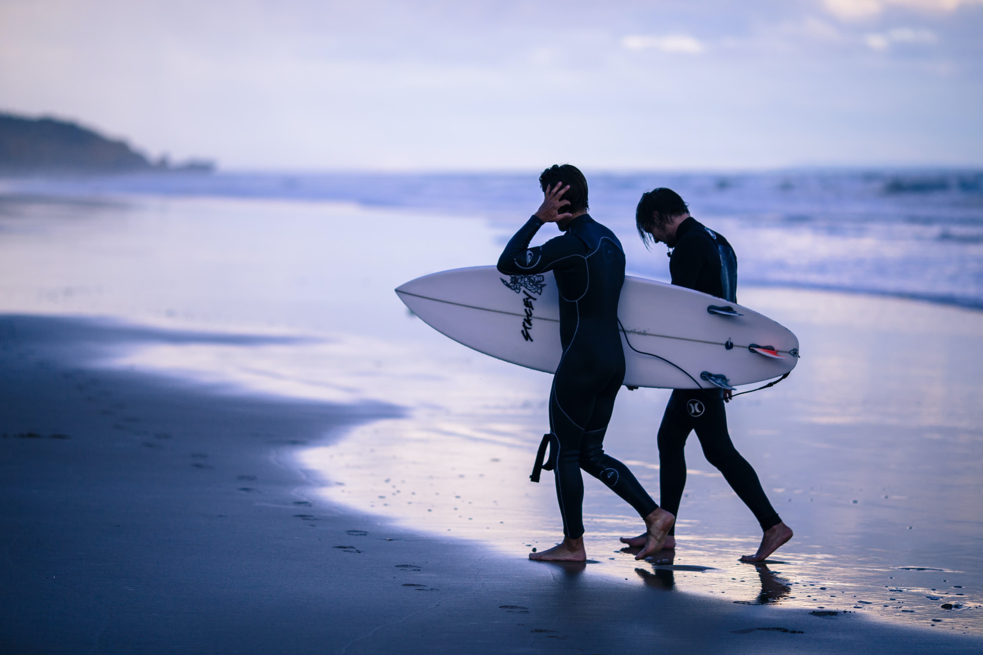 Two friends coming out of the water after a long session.